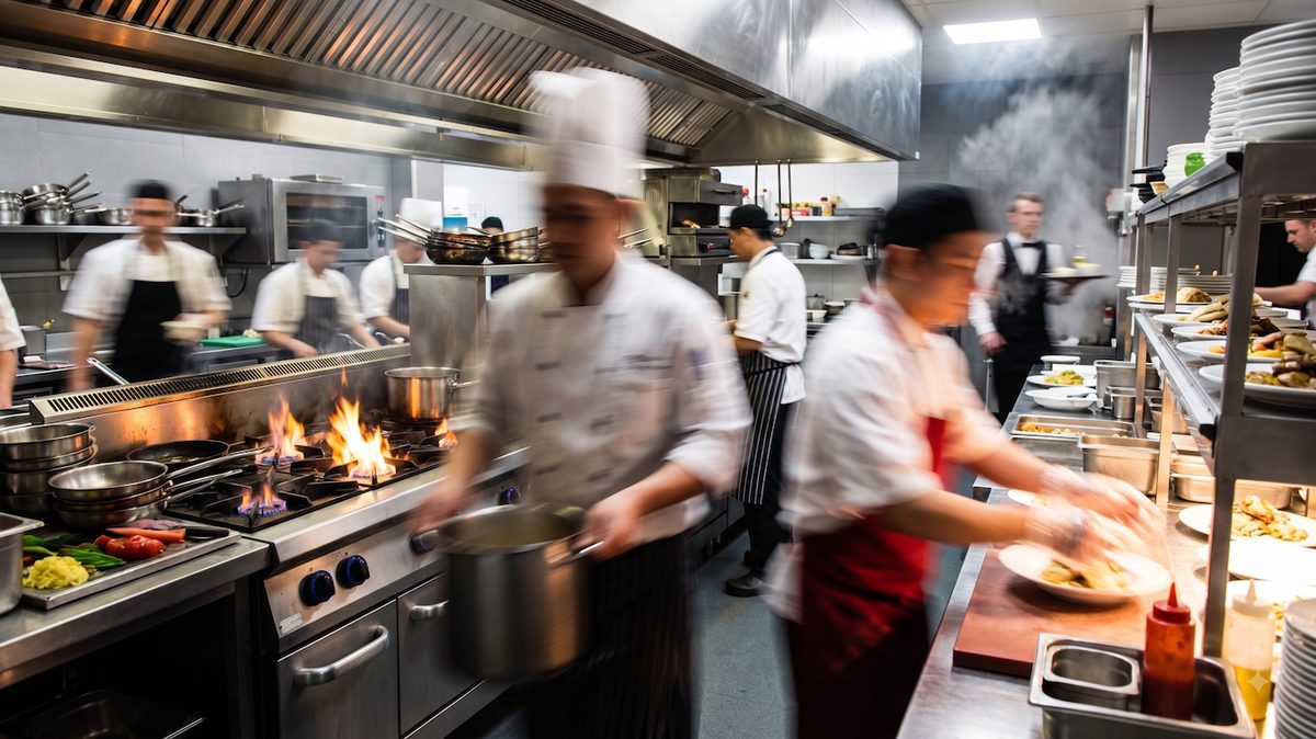 Cocina profesional en plena actividad con cocineros trabajando junto a los fogones